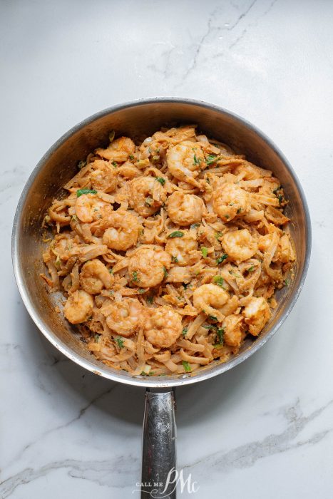 A skillet filled with shrimp and noodles.